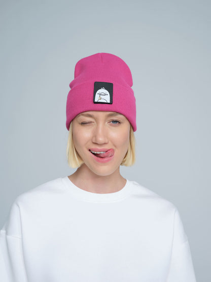 A person wearing a pink beanie with a 'duck' animal design on the fold, part of a white crew neck sweater.