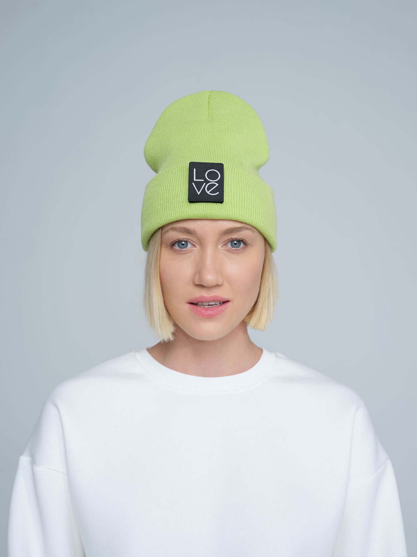 model wearing light green patch ready beanie with LOVE text patch on the front 