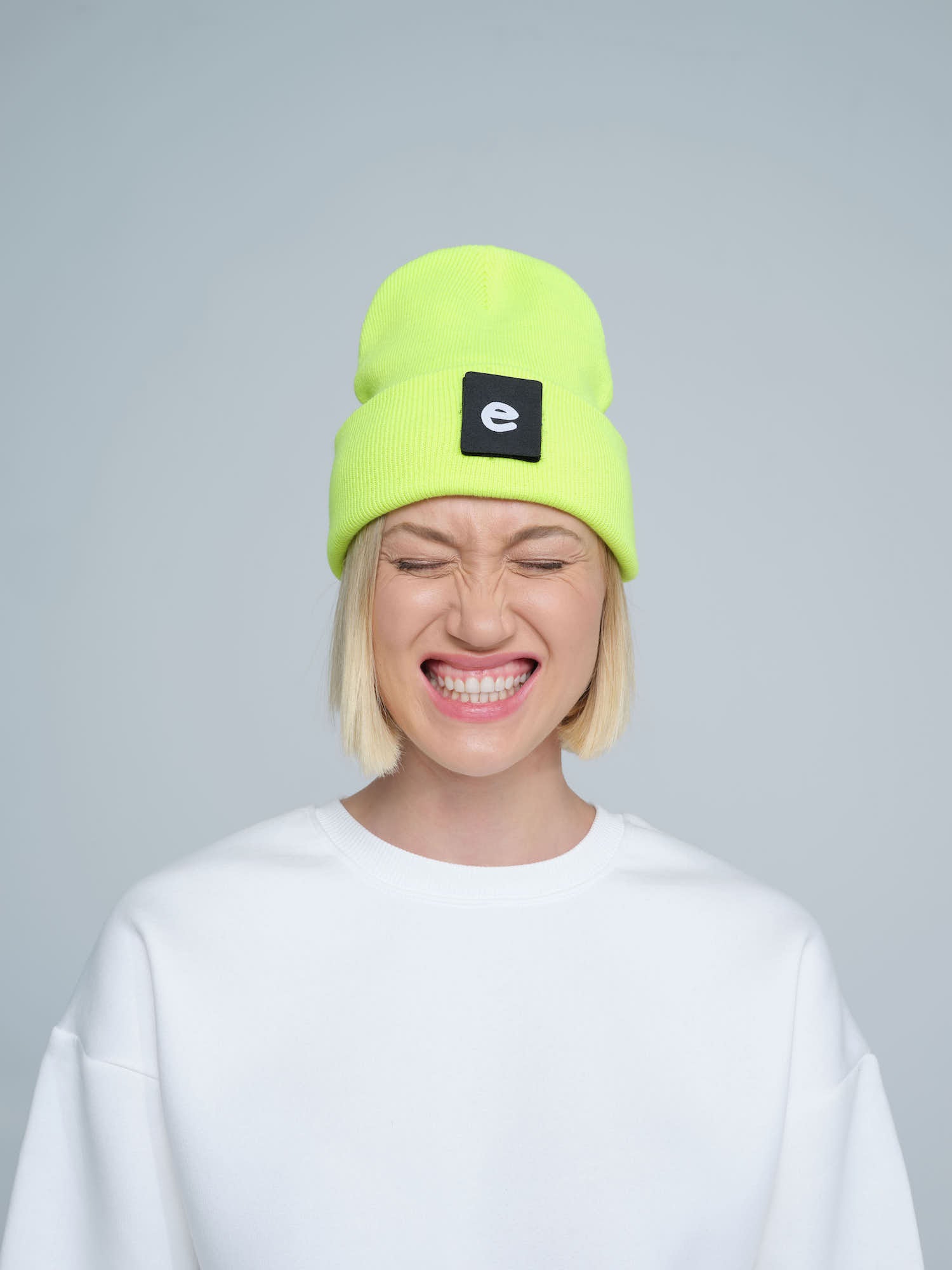 women wearing neon yellow beanie with a 'e' letter patch on it 