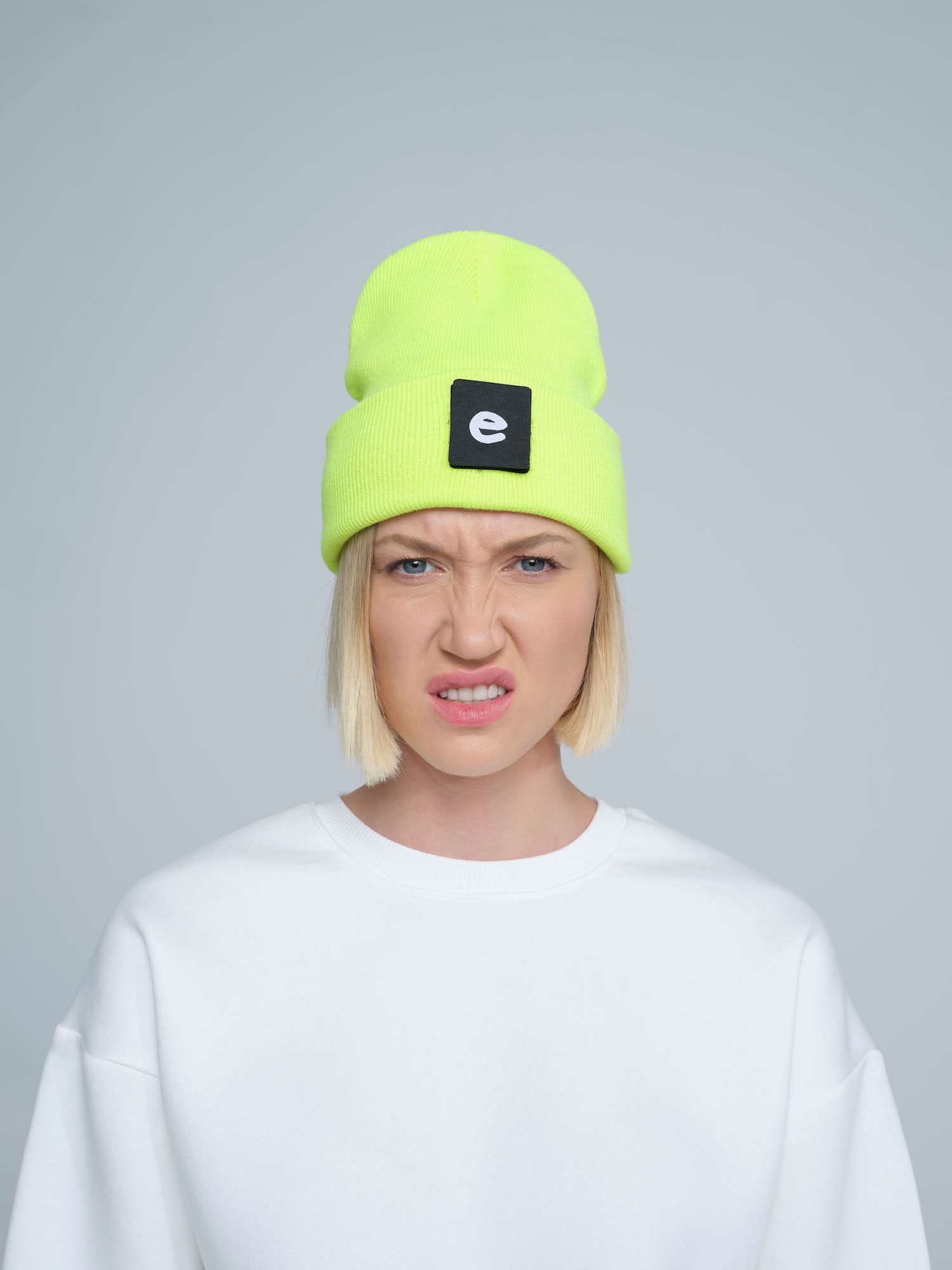women wearing neon yellow beanie with a 'e' letter patch on it 
