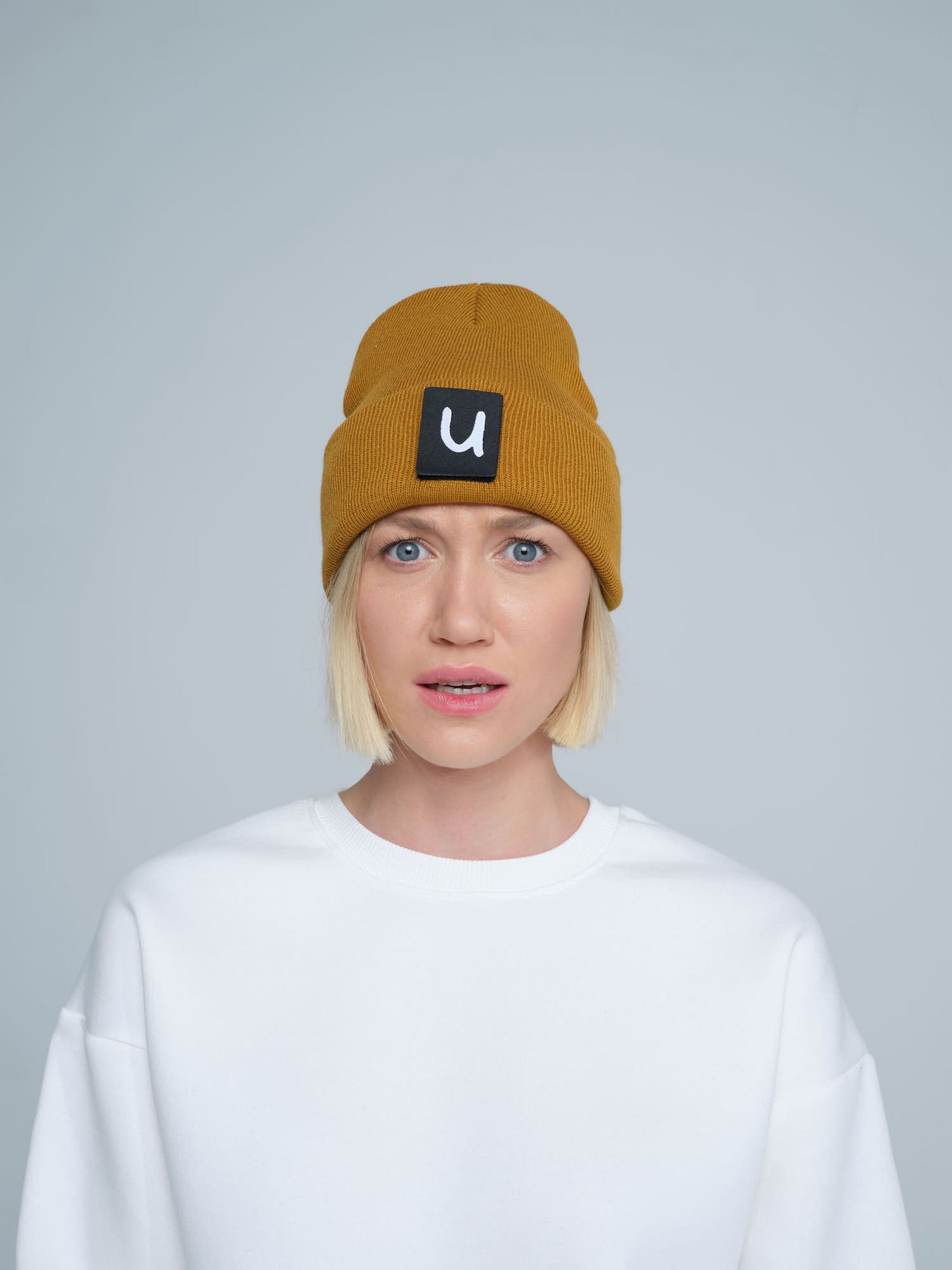 model wearing peru colour beanie with 'u' letter patch on it
