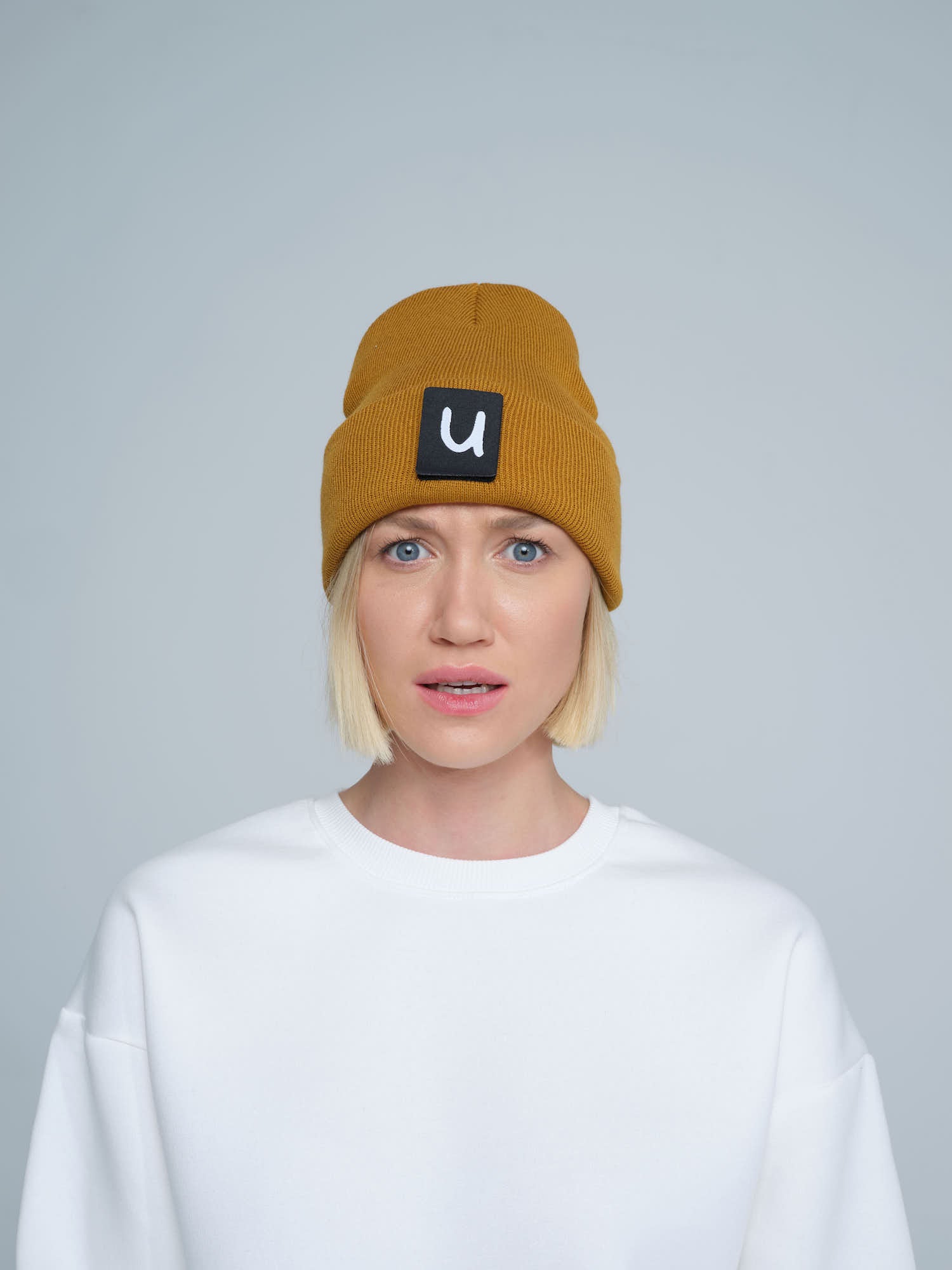 model wearing peru colour beanie with 'u' letter patch on it