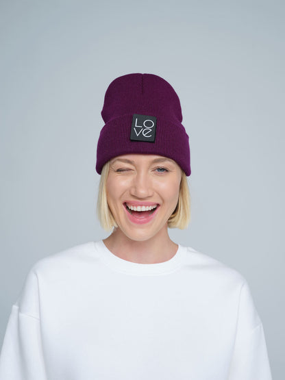 A person wearing a purple beanie hat with a 'Love' logo on the front with a smiling face.