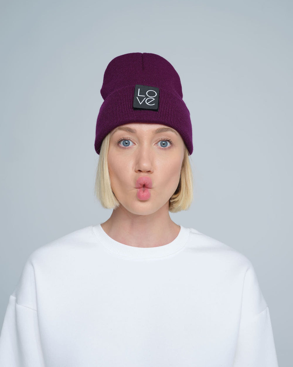A person wearing a purple beanie hat with a 'Love' patch on the front.