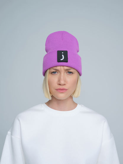 A person wearing a tulip purple beanie hat with a design on the fold.