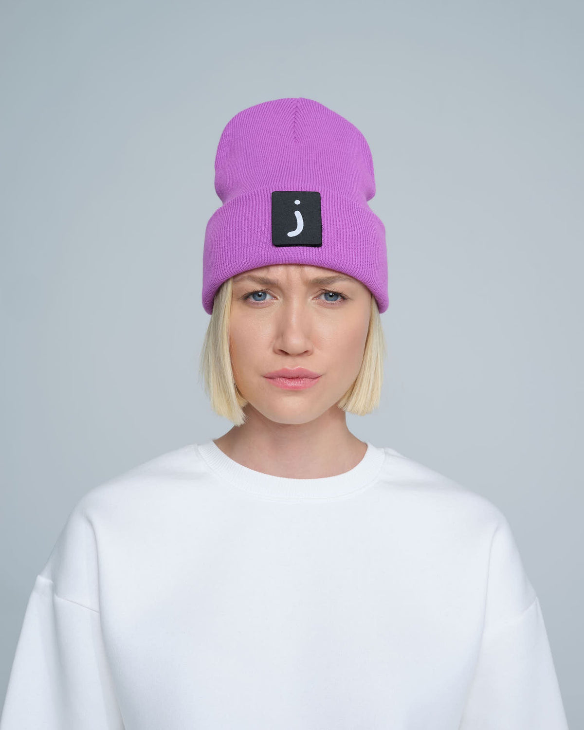 A person wearing a tulip purple beanie hat with a design on the fold.