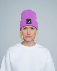 A person wearing a tulip purple beanie hat with a design on the fold.